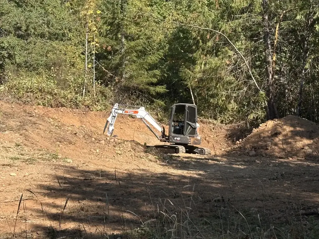 Excavator removing fallen trees and brush from a Sequim property