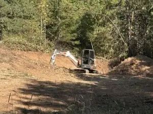 Excavator removing fallen trees and brush from a Sequim property